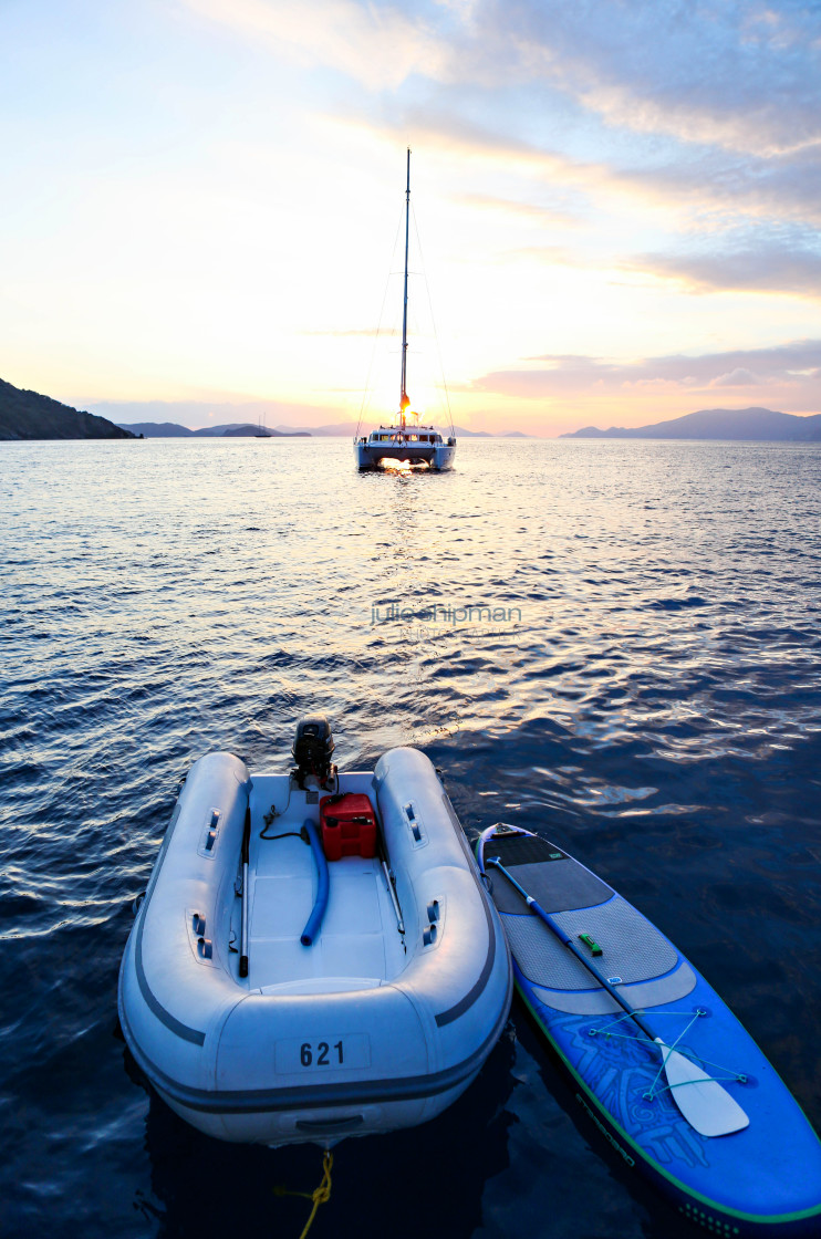 "The dinghy and SUP are at rest behind the boat at sunset in the BVI." stock image