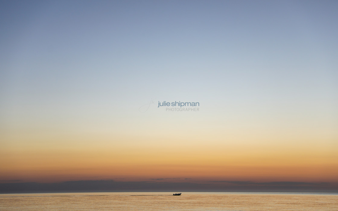 "Fishing boat heading out at sunrise." stock image