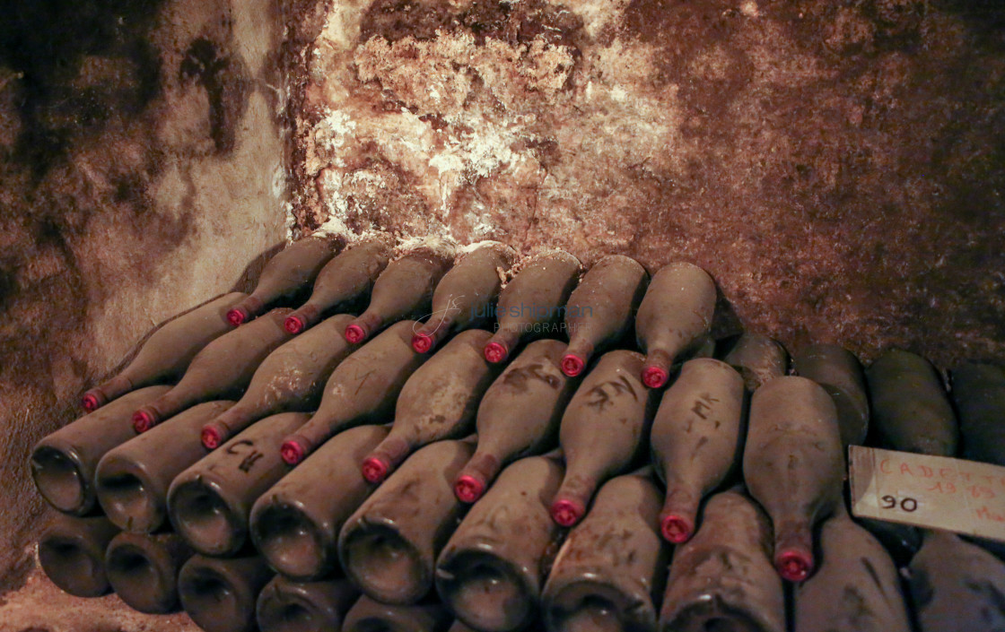 "Aged bottles of wine stacked up against a wall in the dark cellars of Chateauneuf Du Pape in France." stock image