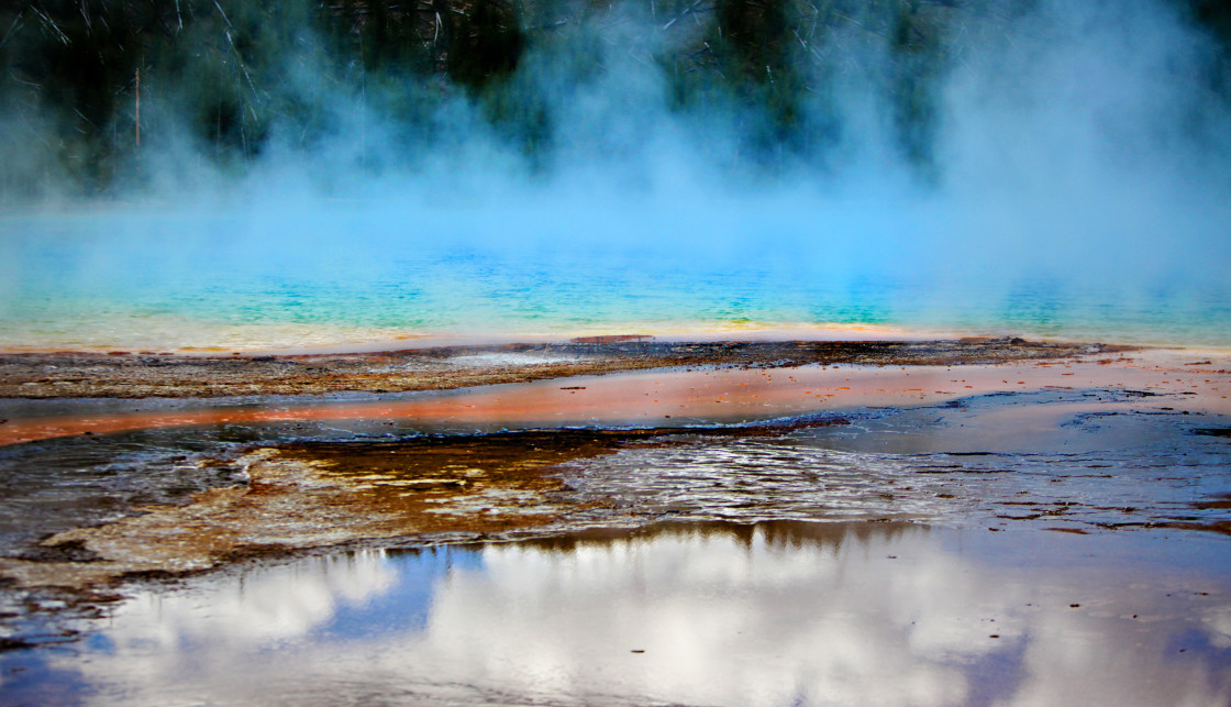 "Intense colors and puffy white clouds in a blue sky create a stunning a unique landscape of the hot springs in Yellowstone National Park, Wyoming." stock image