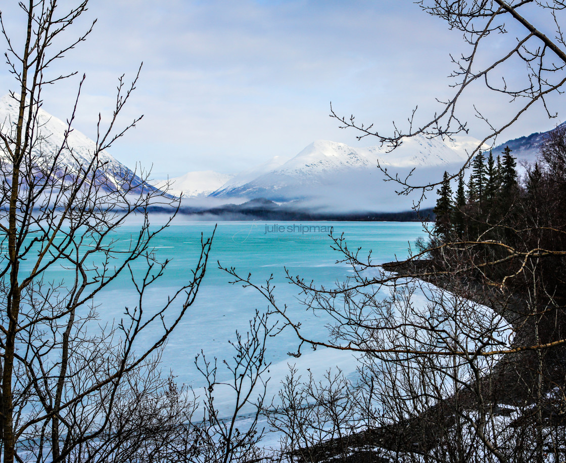 "Image of a late winter lake with clouds and mist surrounding the mountains in Alaska." stock image