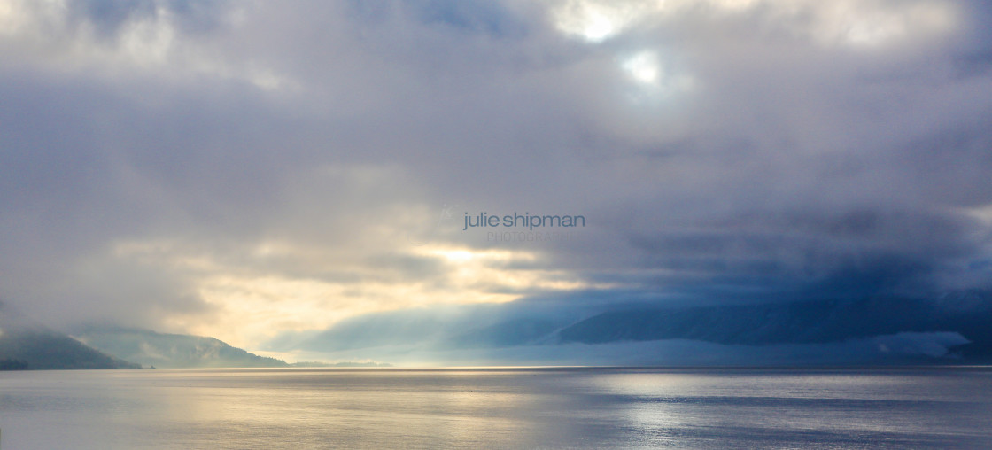 "Image of a late winter lake with clouds and mist surrounding the mountains in Alaska." stock image