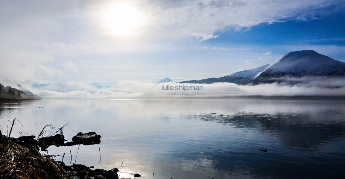 "Image of a late winter lake with clouds and mist surrounding the mountains in Alaska." stock image