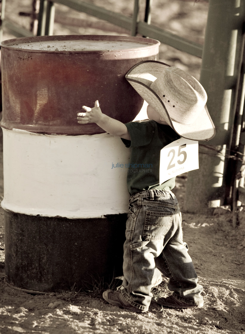 "Young cowboy wraps his arms around a barrel at a rodeo during adventures of The West in Robertson, Wyoming and the ranches in the Bridger Valley." stock image