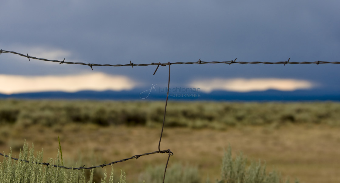 "Barbed wire fence with a storm approaching in The West in Robertson, Wyoming and the ranches in the Bridger Valley." stock image