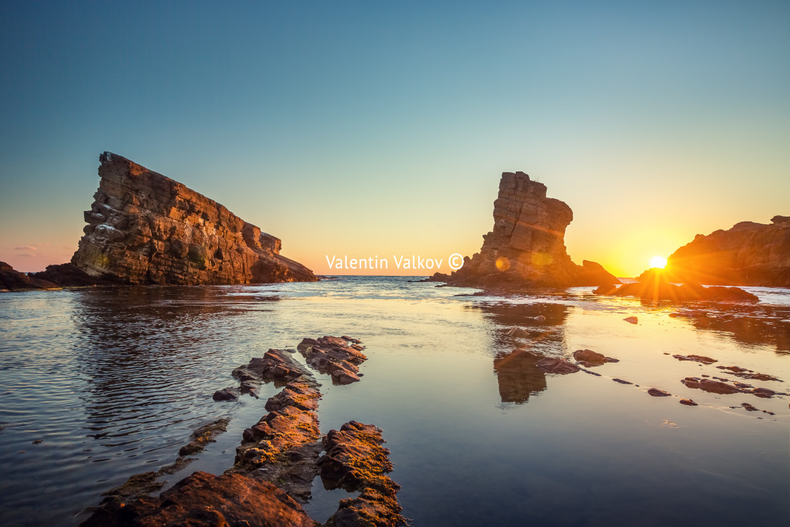 "Dramatic sunrise with mist on the beach with rocks" stock image