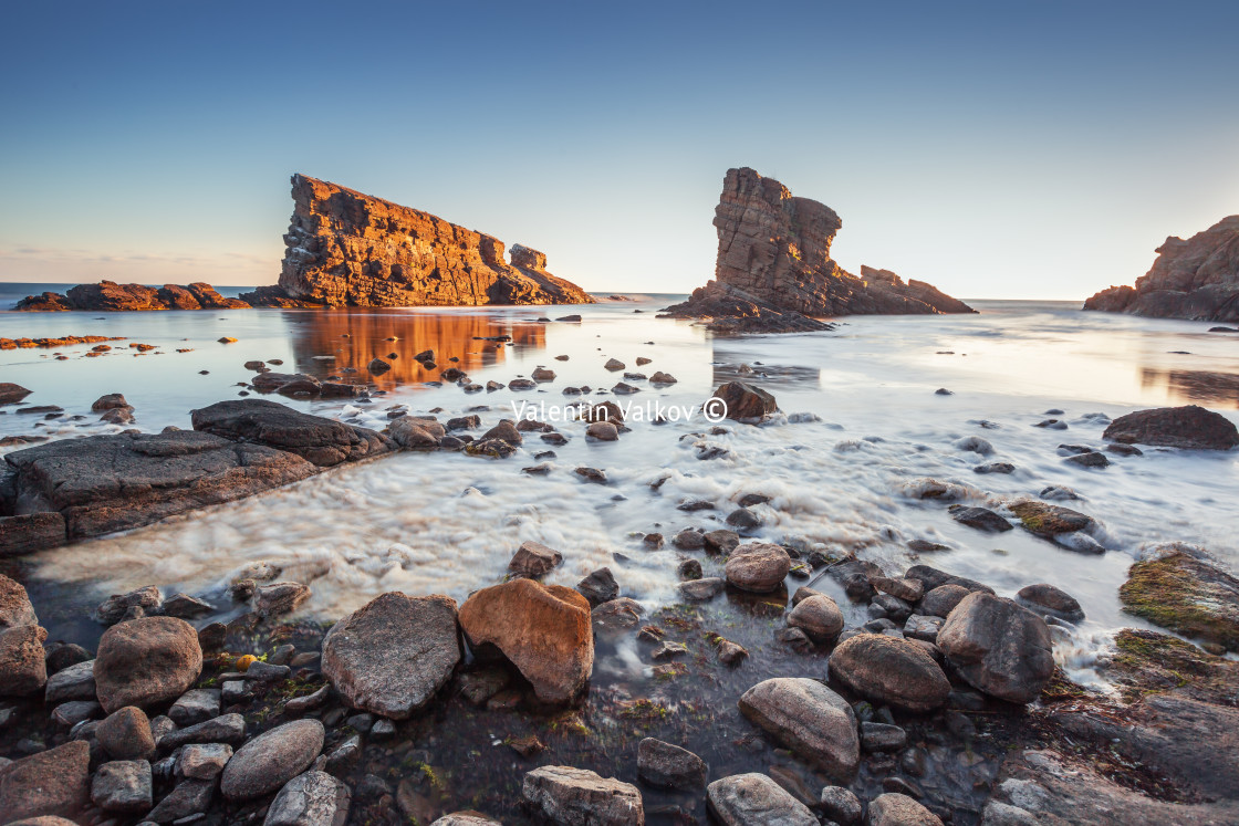 "Dramatic sunrise with mist on the beach with rocks" stock image