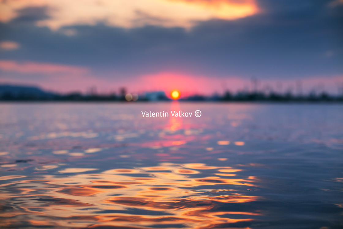 "Sunset light shining on ocean wave with orange tones" stock image
