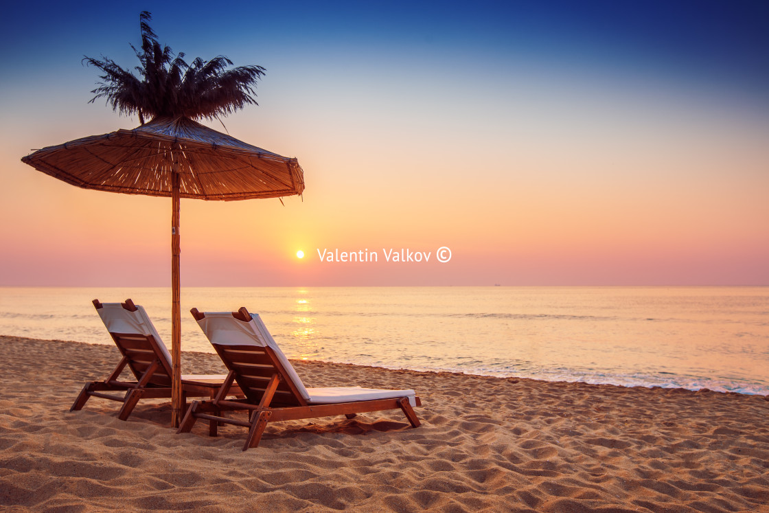 "Vivid sunrise on a beautiful sandy beach with sunshade" stock image