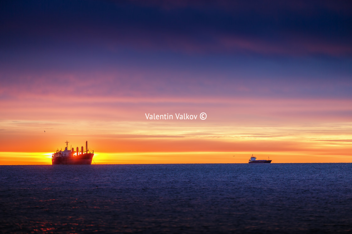 "Sunrise over the sea with sailing cargo ship" stock image