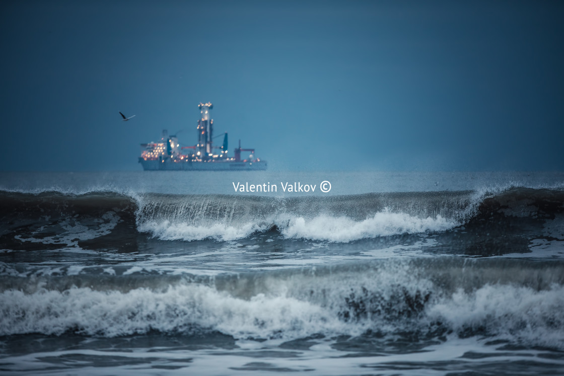 "International Container Cargo ship in the sea water after sunset" stock image