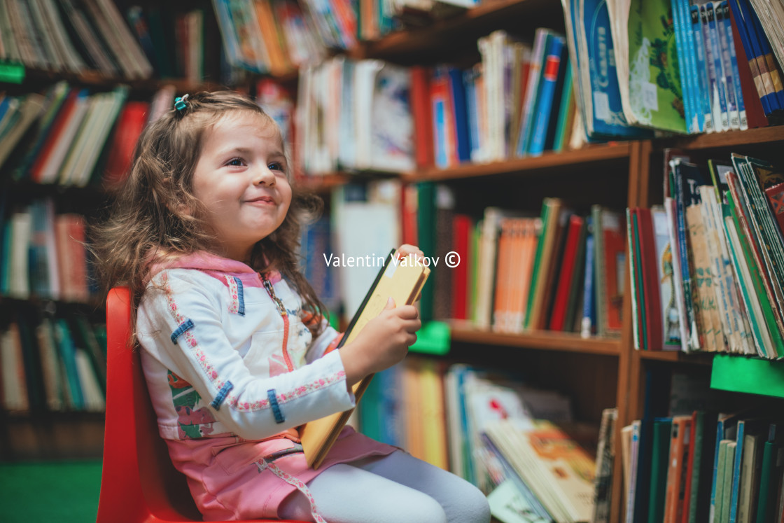 "Cute girl reading book in library" stock image