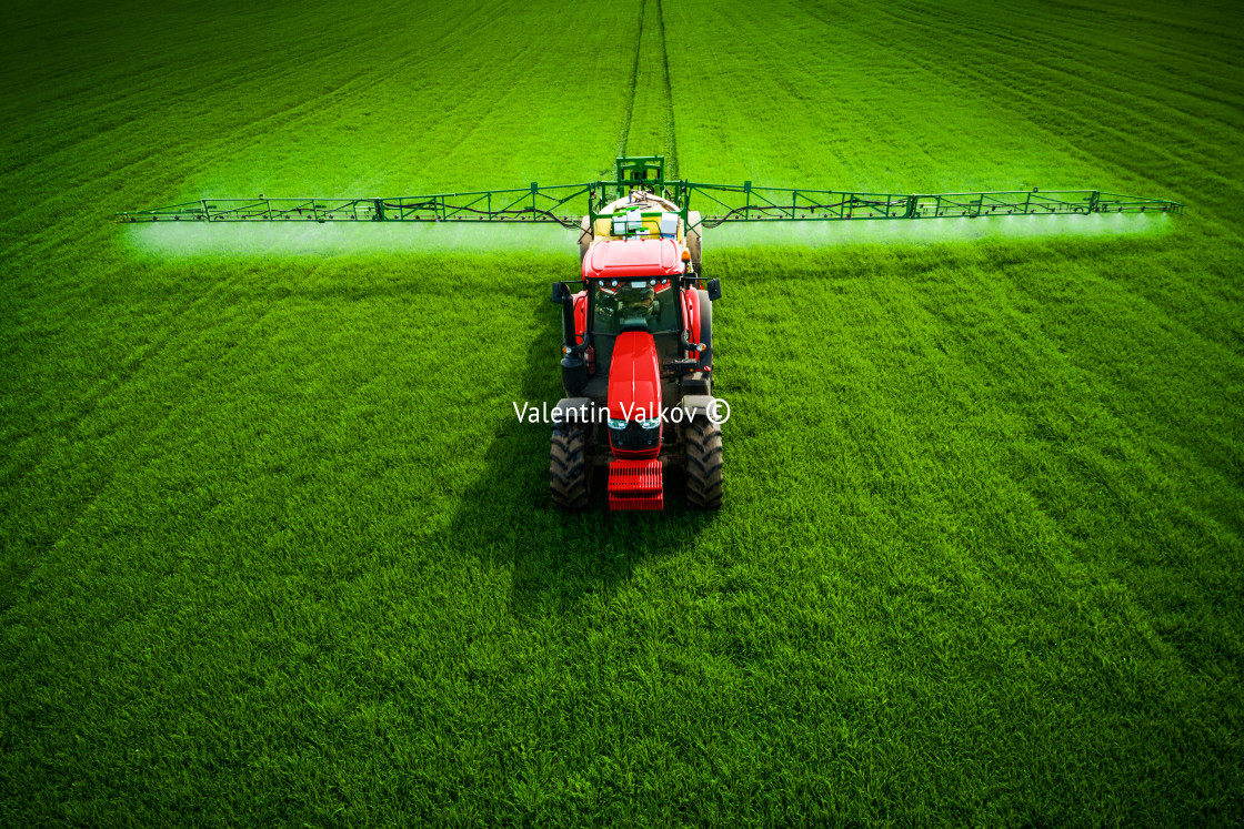 "Aerial view of farming tractor plowing and spraying on field" stock image