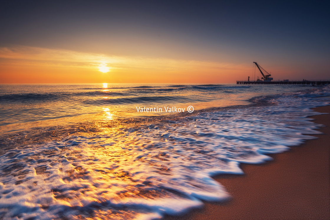 "Sunrise on the sea and beach. Waves washing the sand. Industrial" stock image