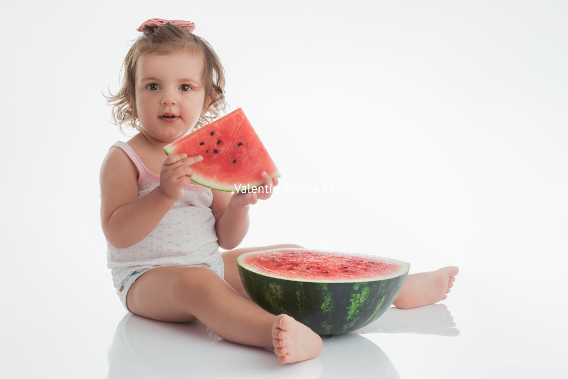 "Baby girl eating watermelon slice isolated on white background" stock image