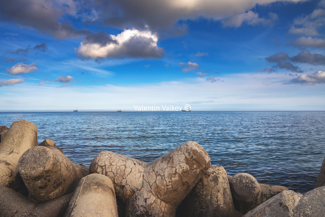 "Seascape stones in sea water and sailing cargo ships" stock image