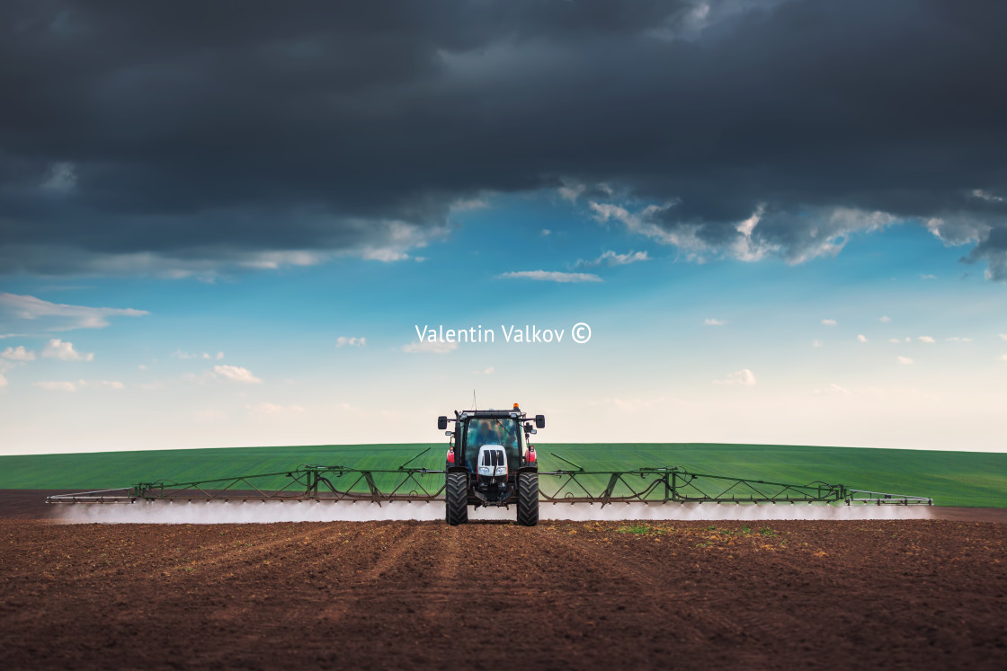 "Farming tractor plowing and spraying on field" stock image