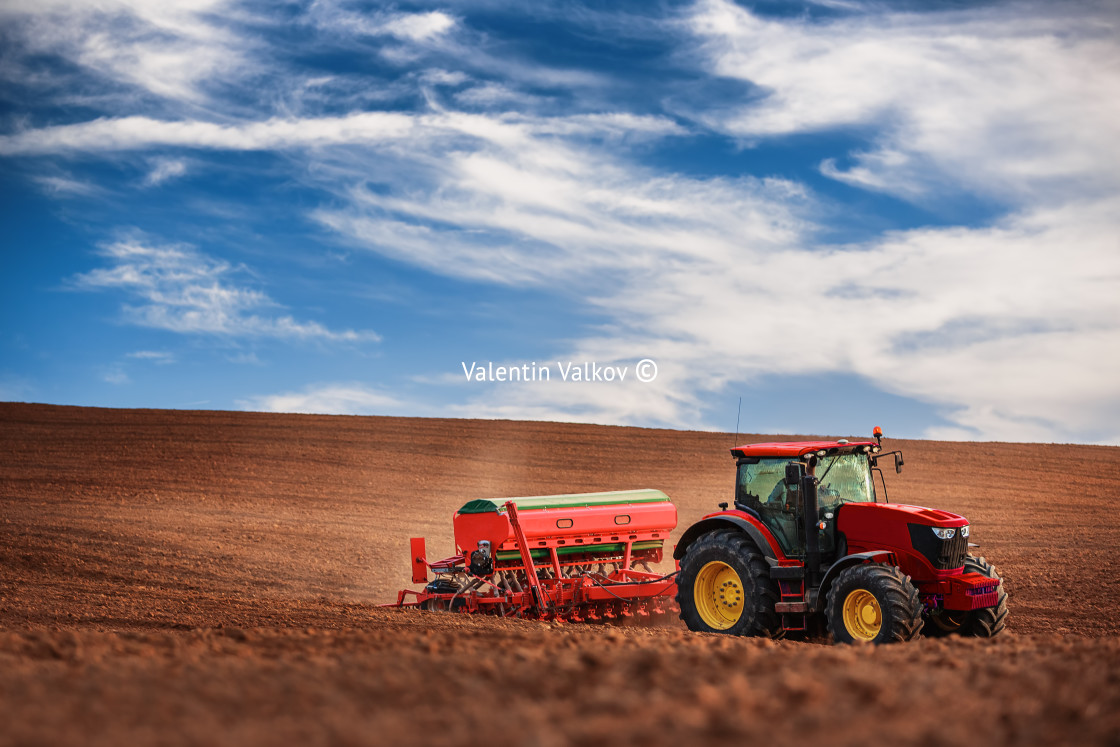 "Farmer with tractor seeding crops at field" stock image