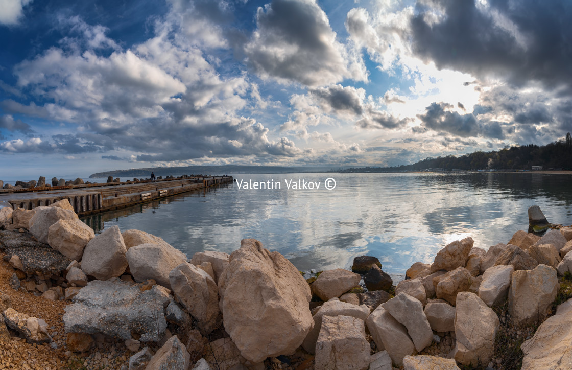 "Seascape stones in sea water. Dramatic clouds and blue sky." stock image