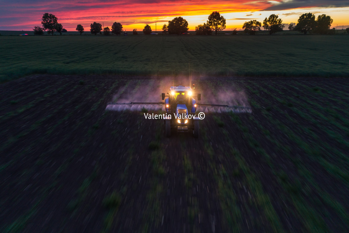 "Tractor spraying field at spring" stock image