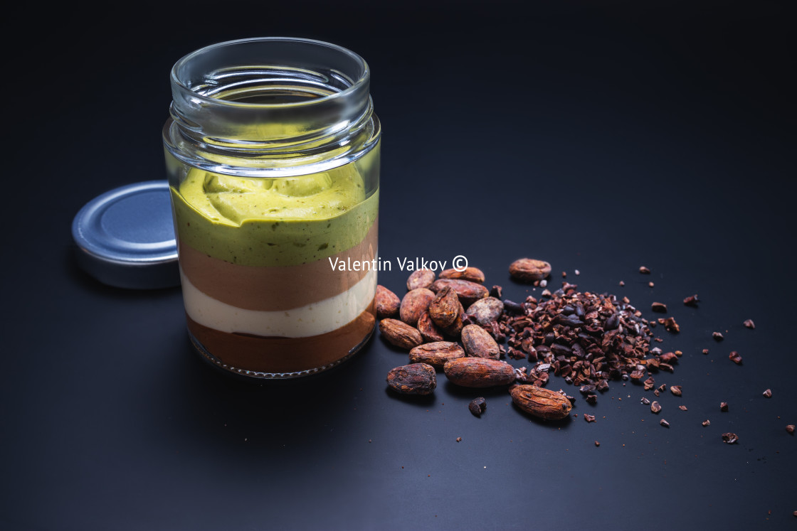 "Milk creamy dessert in jar with nuts, chocolate and cacao beans" stock image