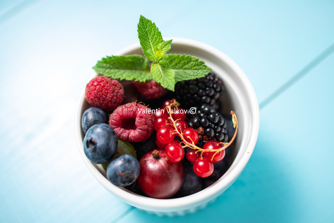 "Wild berry fresh fruits with mint leaf in a cup on wooden vintag" stock image