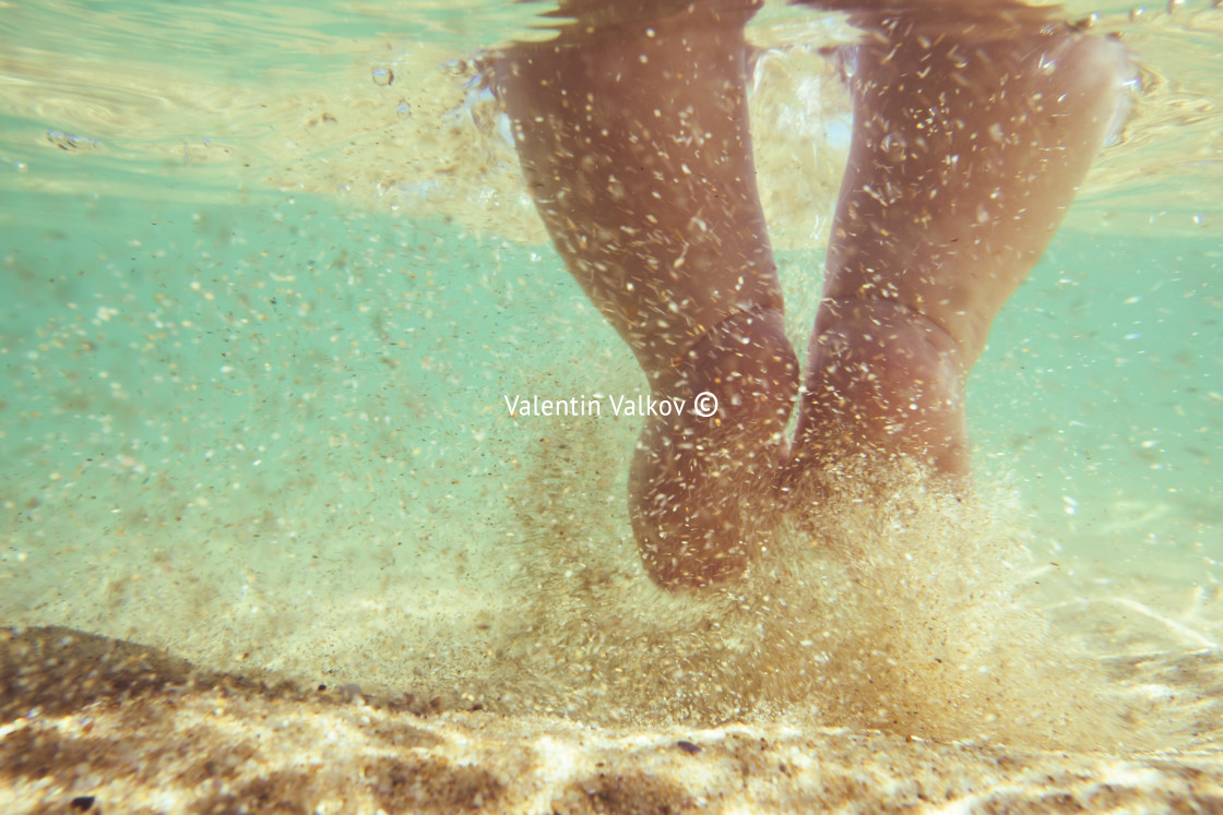 "Little infant baby child legs and toes touch sand on sea beach" stock image