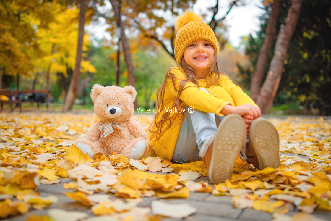 "Happy little girl playing with his teddy bear toy in autumnal pa" stock image