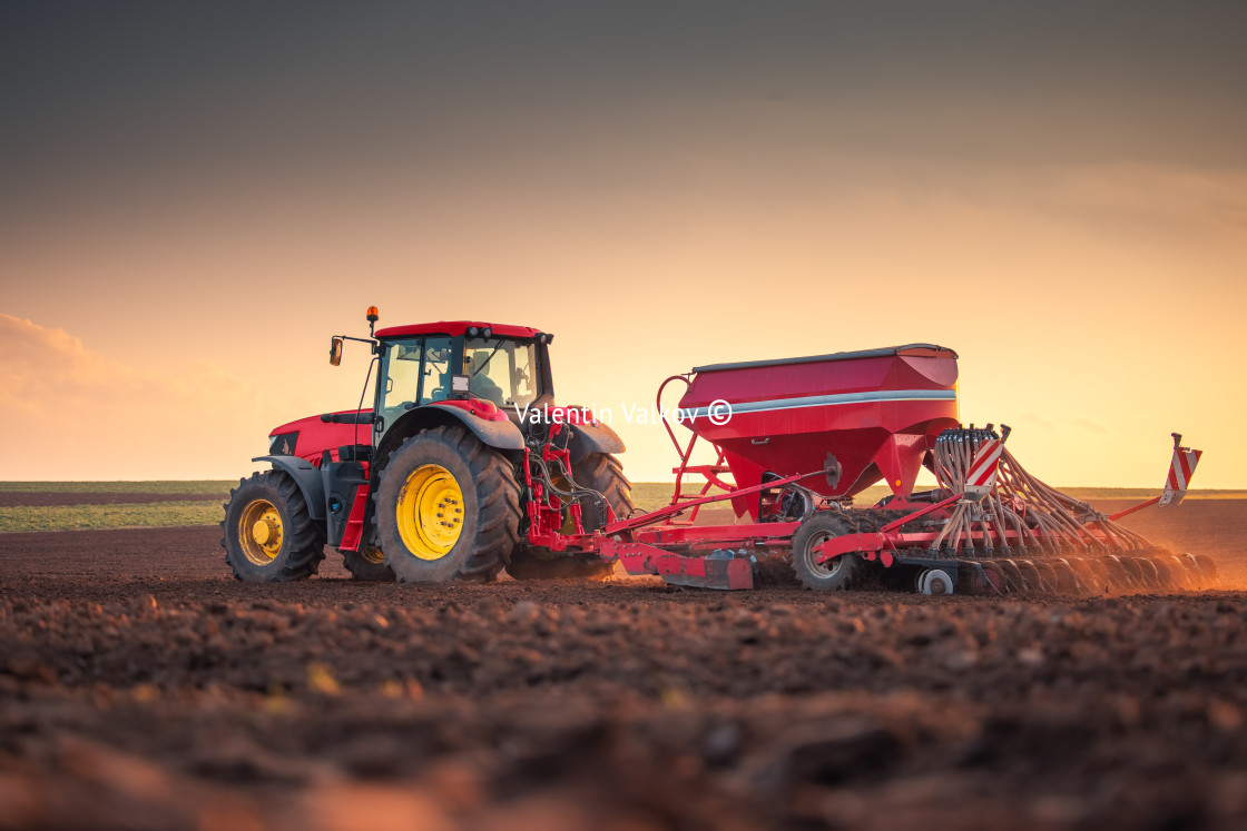 "Farmer with tractor seeding crops at field" stock image