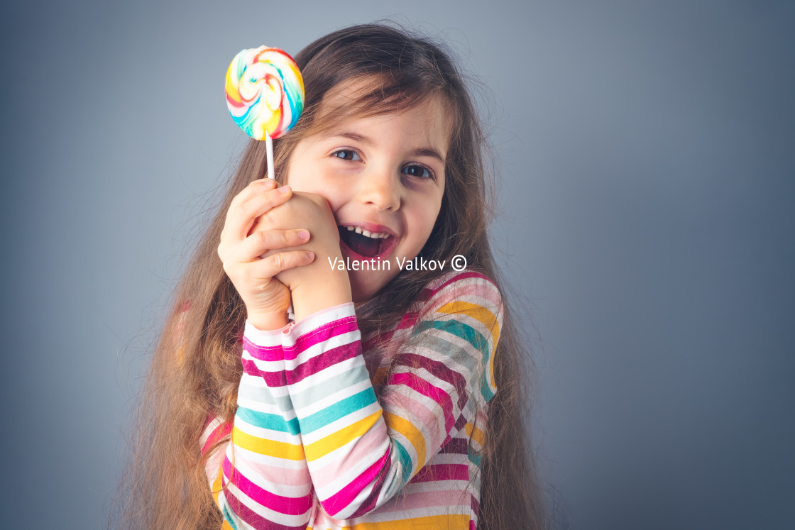 "Little kid eating lollipop. Happy beautiful girl with candy isol" stock image