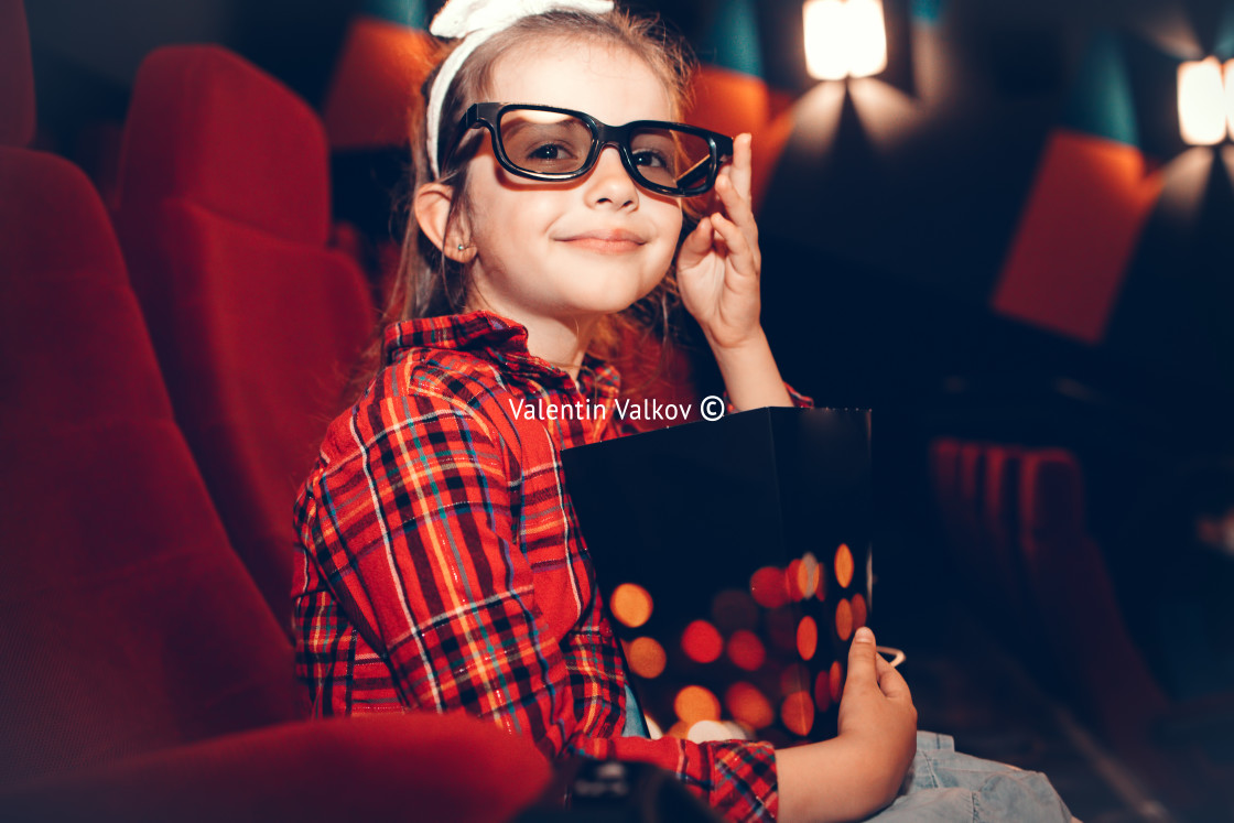 "Little girl watching cartoon 3D movie in cinema and eating popco" stock image