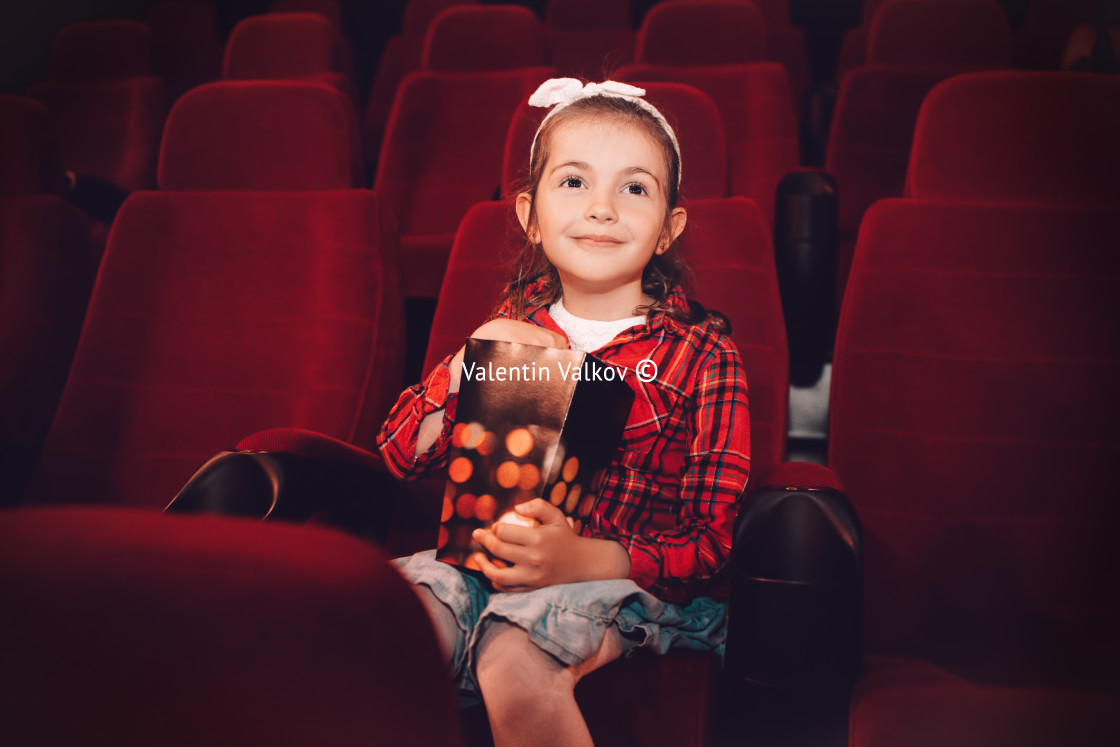 "Little girl watching cartoon 3D movie in cinema and eating popco" stock image