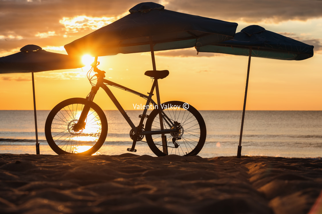 "Silhouette of Beach Umbrellas with bike, sunrise shot." stock image