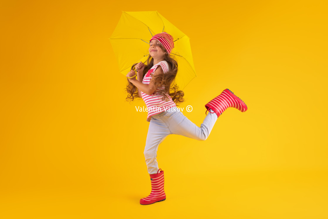 "Girl with rubber boots for rain and umbrella over yellow backgro" stock image