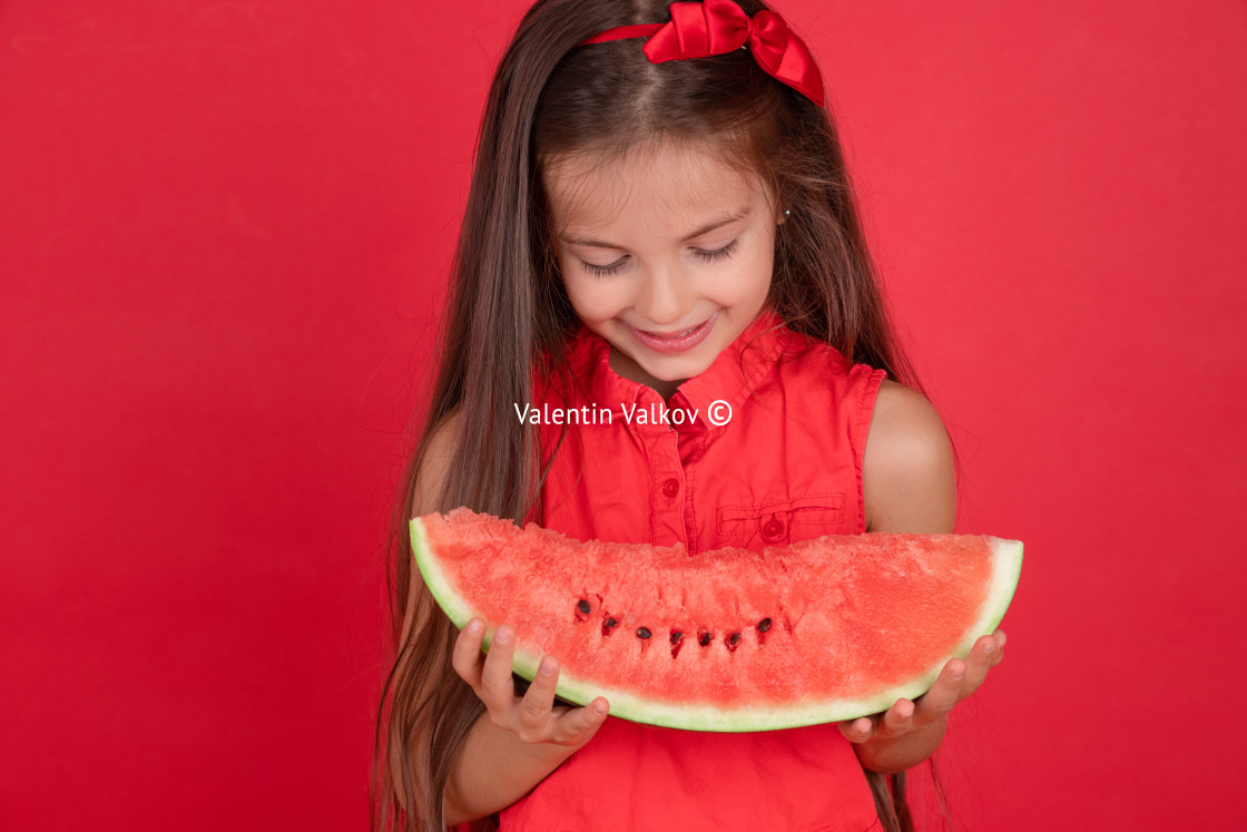 "Cute little girl holding, eating juicy slice of watermelon over" stock image