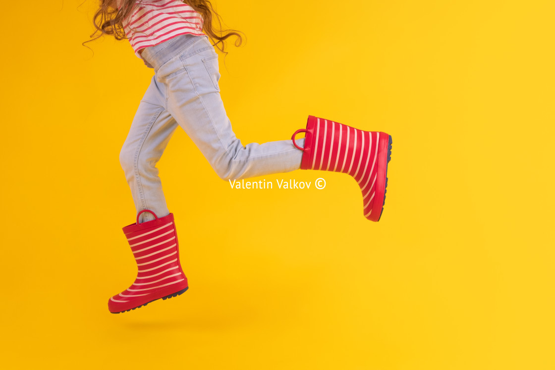 "Girl with red rubber boots for rain over yellow background" stock image