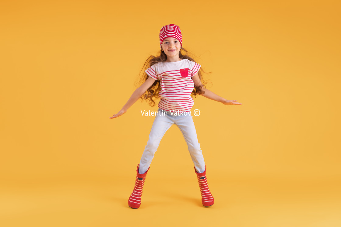 "Happy emotional girl jumping on colored yellow background. Autum" stock image