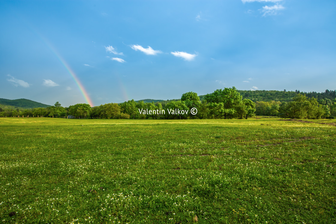 "Rainbow over fields and trees on a farm on the edge of Lake" stock image