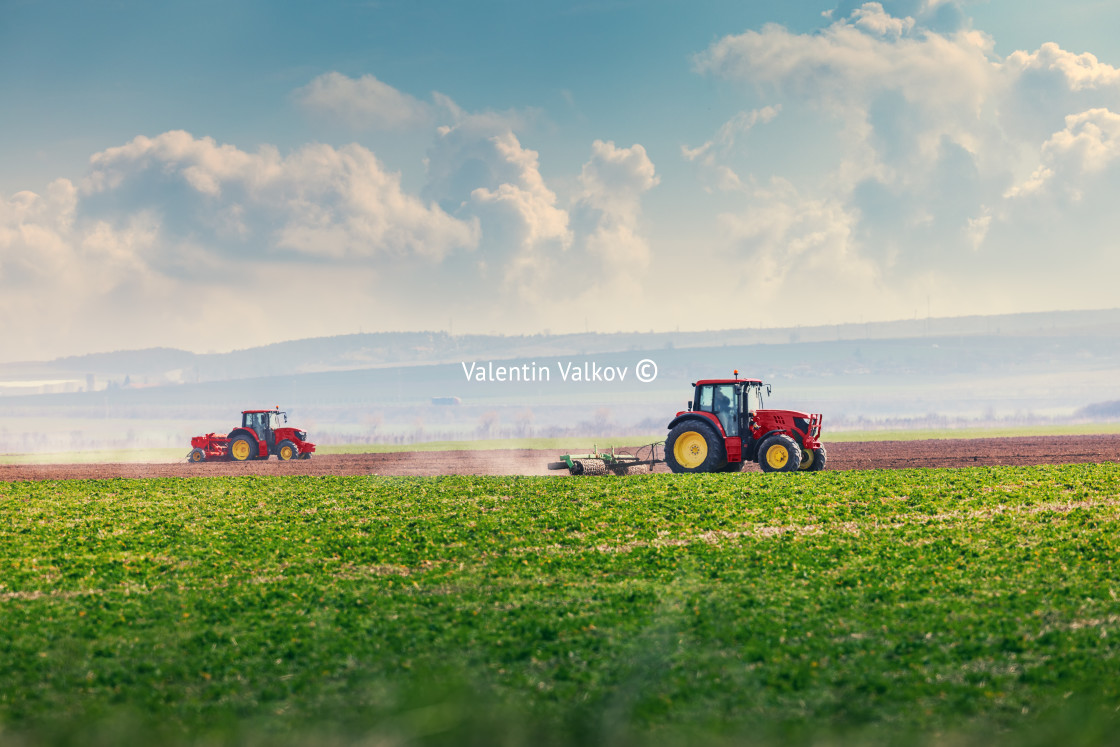 "Farmer with tractor seeding crops at field" stock image