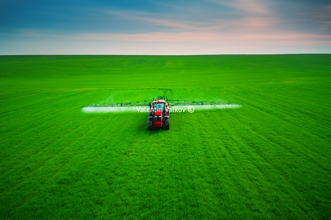 "Aerial view of farming tractor plowing and spraying on field" stock image