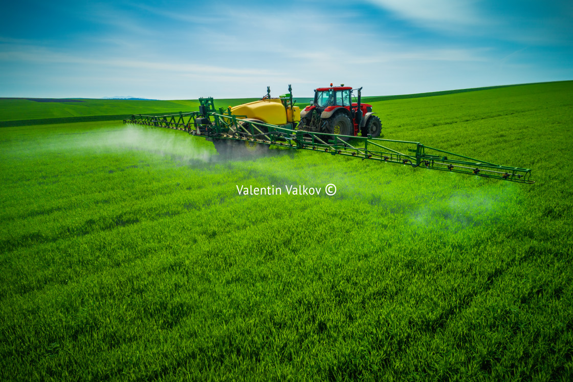 "Aerial view of farming tractor plowing and spraying on field" stock image