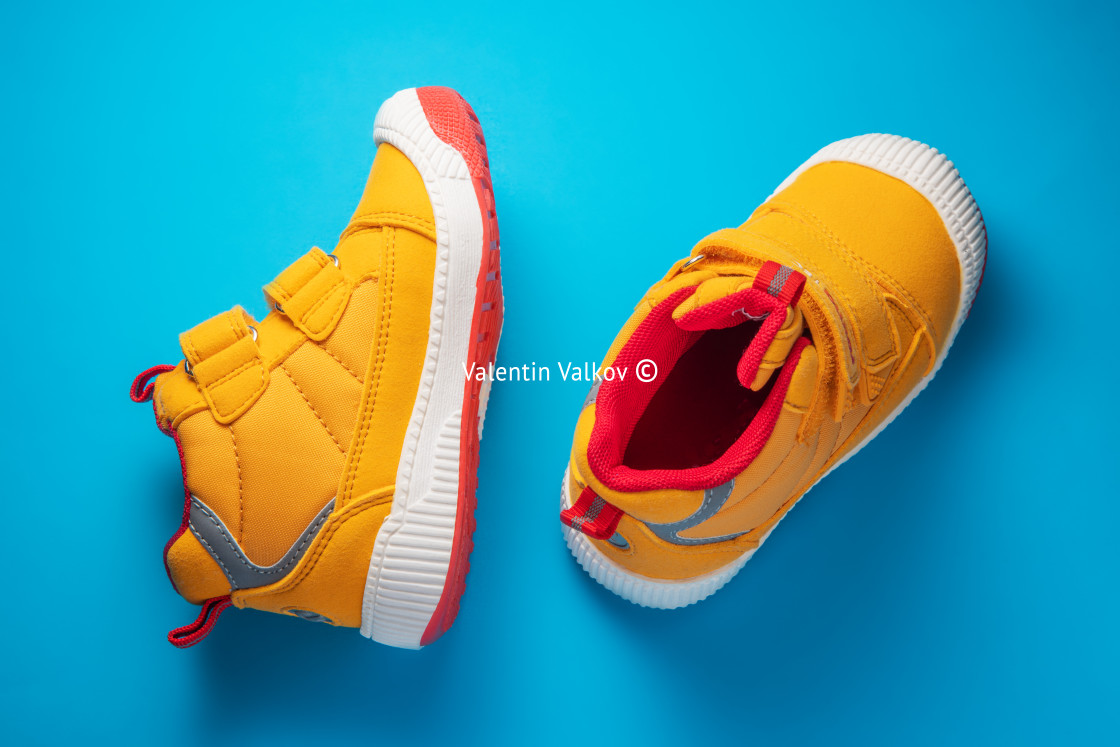 "Yellow baby shoes. Kids sport sneakers isolated on blue backgrou" stock image