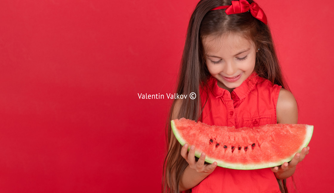 "Cute little girl holding, eating juicy slice of watermelon over" stock image