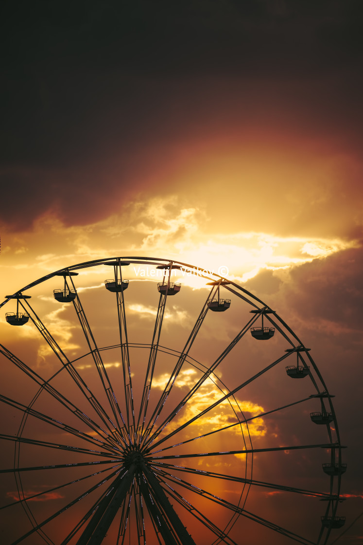 "Ferris Wheel in amusement park and scenic sunset clouds in sky a" stock image