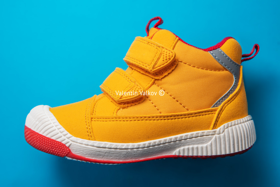 "Yellow baby shoes. Kids sport sneakers isolated on blue backgrou" stock image