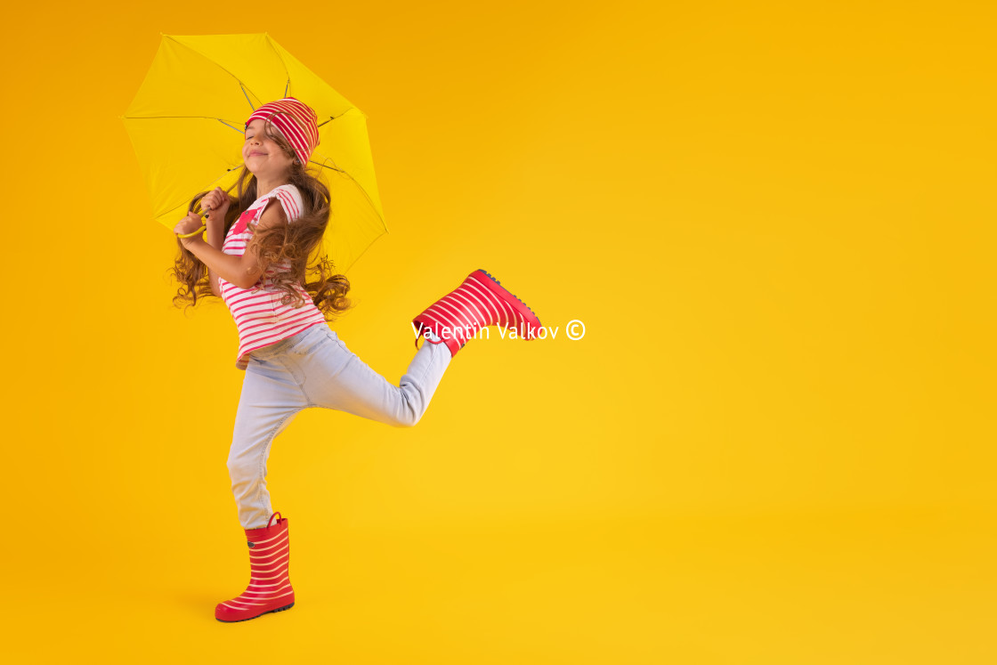 "Girl with rubber boots for rain and umbrella over yellow backgro" stock image