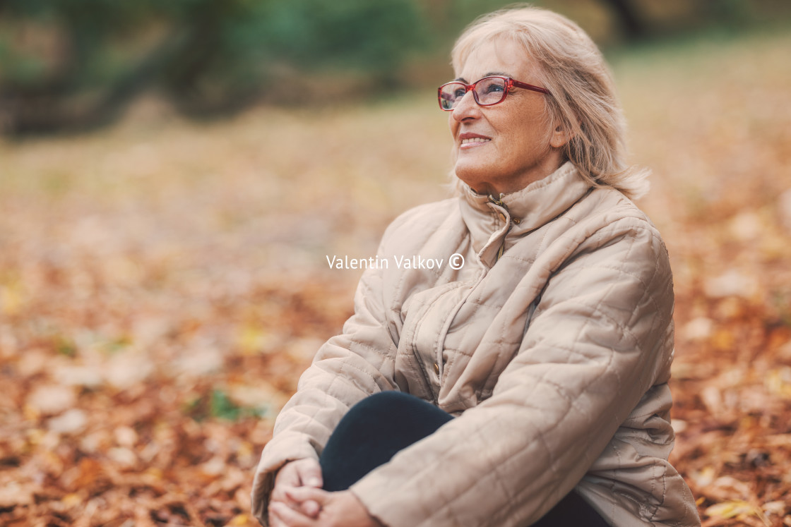 "Happy beautiful senior woman enjoying nature in park in autumn" stock image