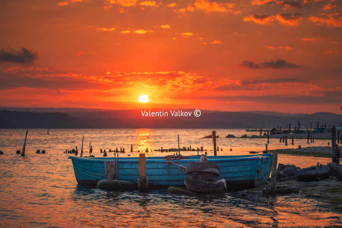 "Sunset over lake, wooden pier and old fishing boat" stock image