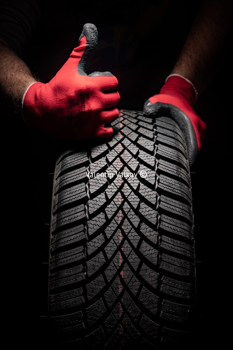 "Car tire service and hands of mechanic holding new tyre on black" stock image