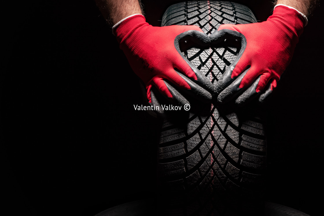 "Car tire service and hands of mechanic holding new tyre on black" stock image